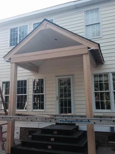 Covered porch structure under construction before patio completion