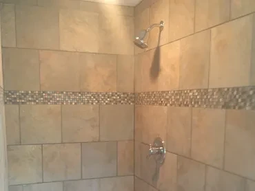 Finished tiled shower with chrome fixtures and mosaic accent band